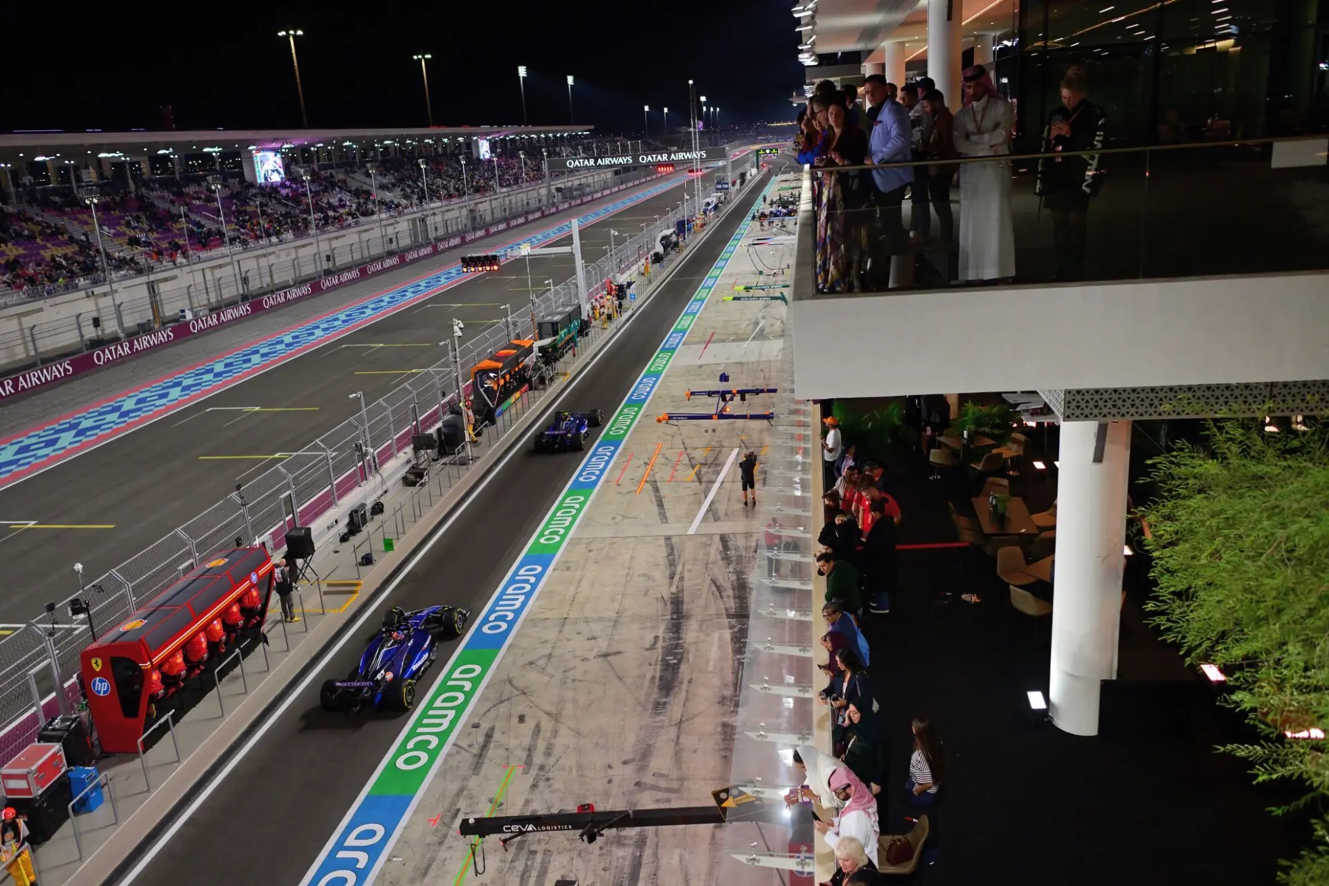 Guests watching Formula 1 cars on the Lusail pit straight from the F1 Paddock Club terrace at night